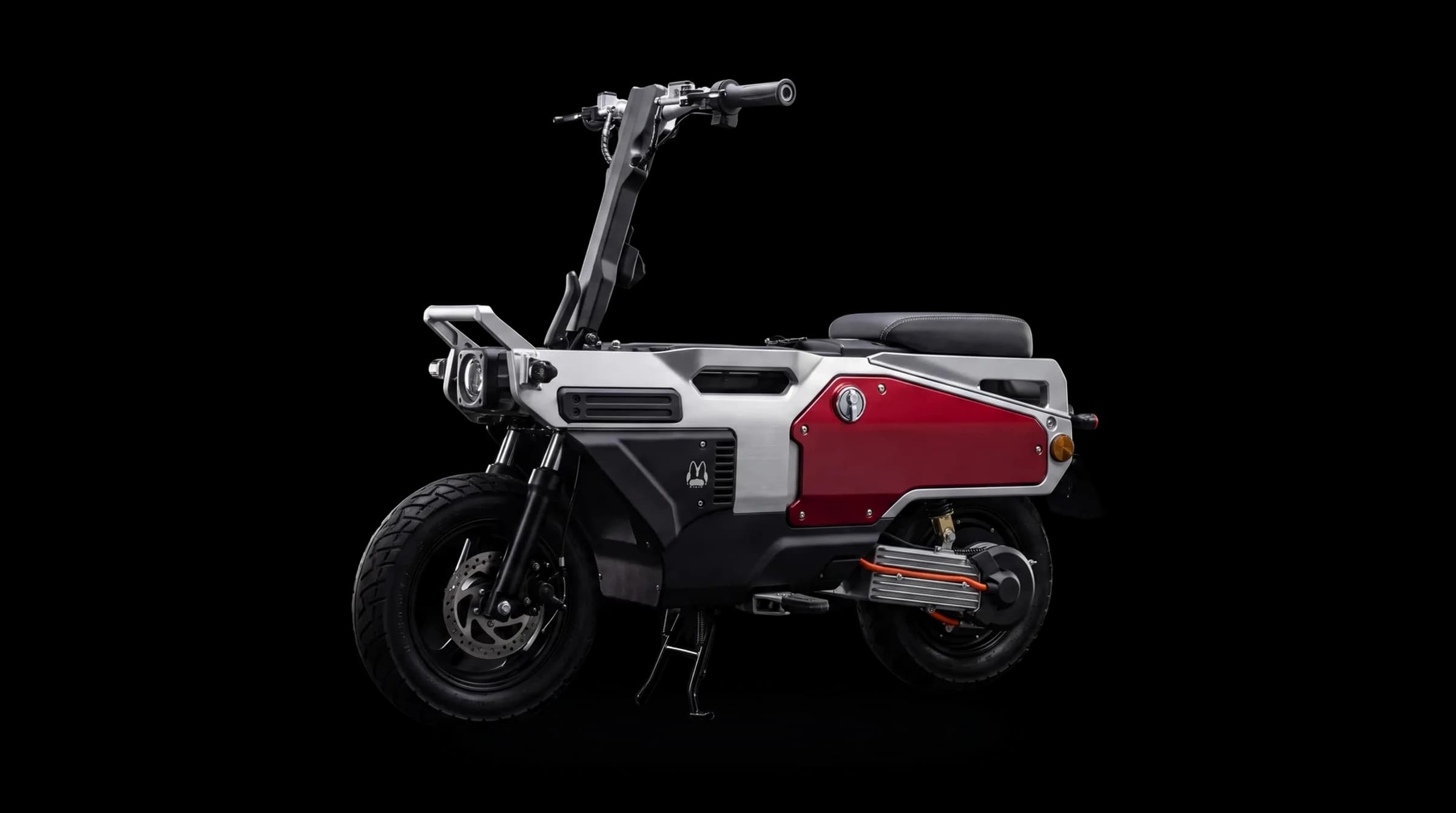 A FELO M1 folding electric motorcycle: brushed aluminium monocoque frame, deep red side access panel, exposed finned rear hub motor.