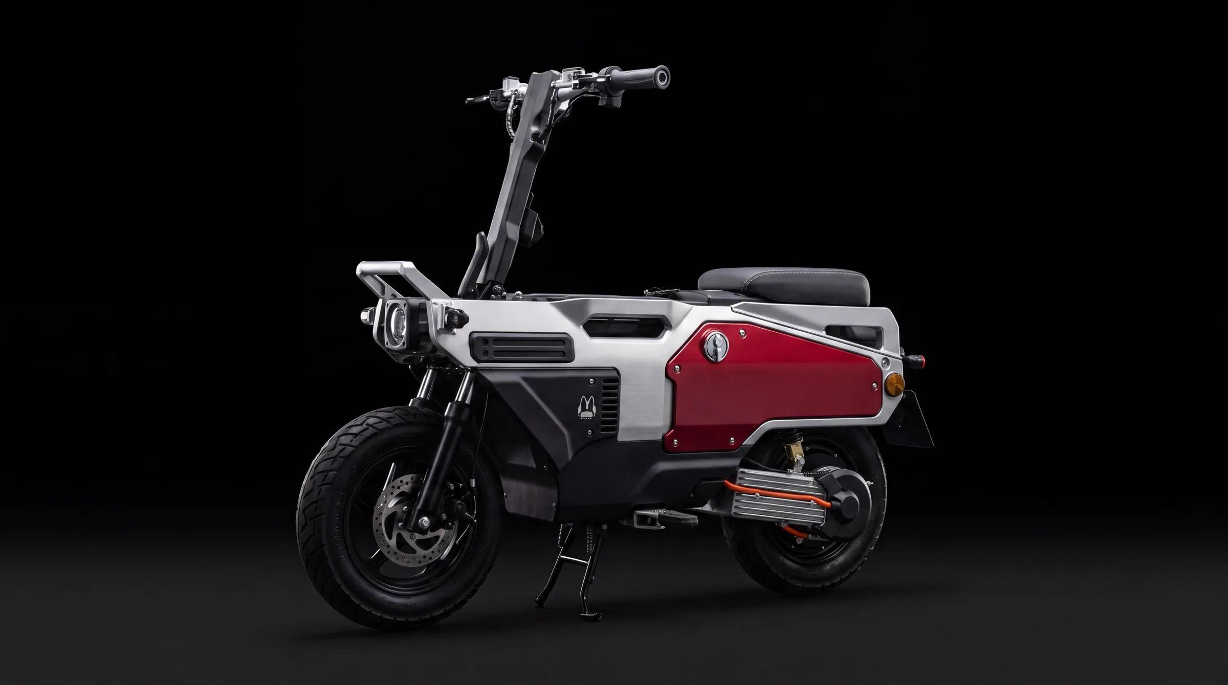 A FELO M1 folding electric motorcycle in a black studio: brushed aluminium monocoque frame, deep red side access panel, exposed finned rear hub motor.
